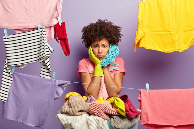 Malestar ama de casa con exceso de trabajo cuelga la ropa en la línea de lavado con pinzas para la ropa