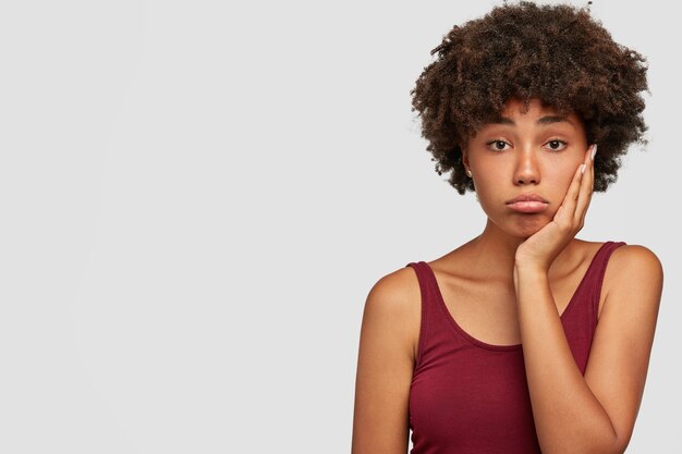 Malestar hermosa mujer afroamericana mantiene la mano en las mejillas, parece disgustado