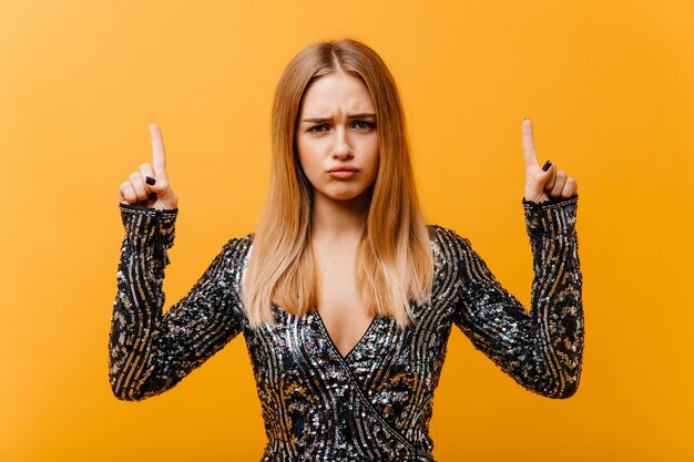 Malestar a mujer increíble en traje de fiesta posando con las manos en alto. retrato de una mujer bastante rubia.