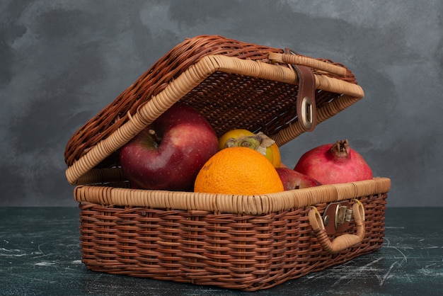 Maleta abierta llena de frutas sobre superficie de mármol.