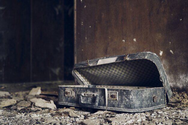 Maleta desgastada dentro de una casa destruida abandonada