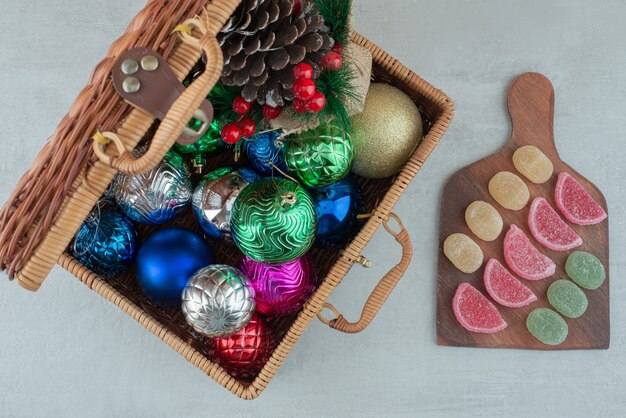 Maleta llena de bolas de Navidad y tablero de madera con mermelada sobre fondo blanco. Foto de alta calidad