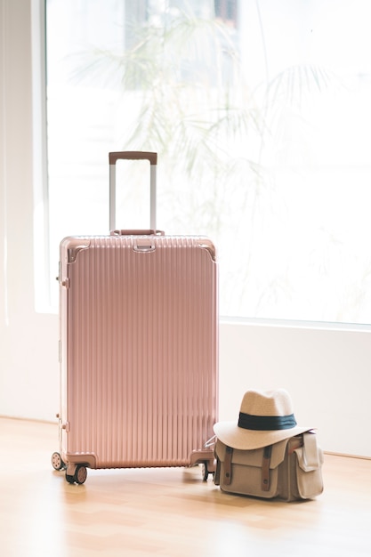 Maleta rosa y bolso y gorro para viajar.
