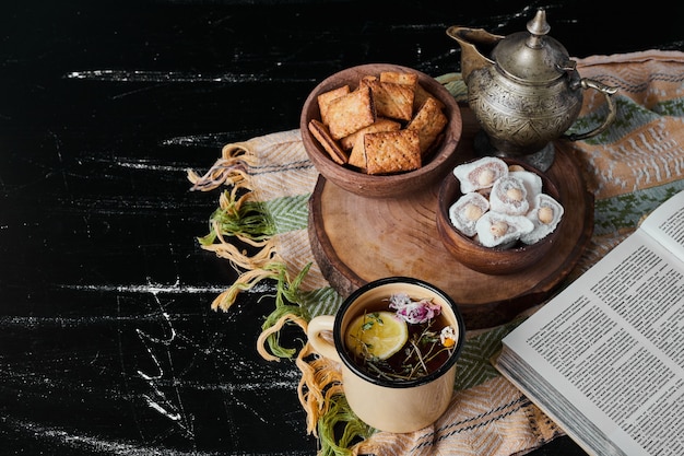 Malvaviscos blancos en una taza metálica con té de hierbas y galletas.