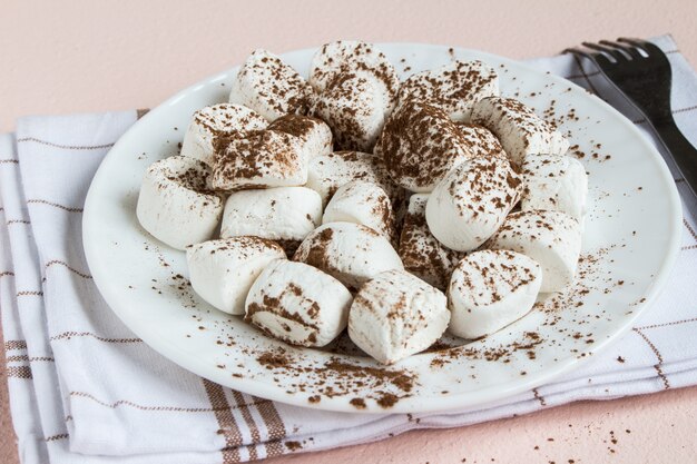 Malvaviscos espolvoreados con cacao en plato blanco