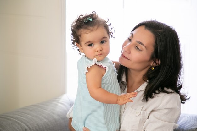 Mamá alegre con dulce hija en brazos. Niña linda a. Copie el espacio. Concepto de paternidad e infancia