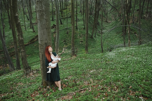 Mamá amamanta a un bebé pequeño en el bosque