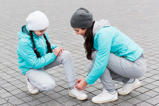 Mamá atando cordones de zapatos para hija