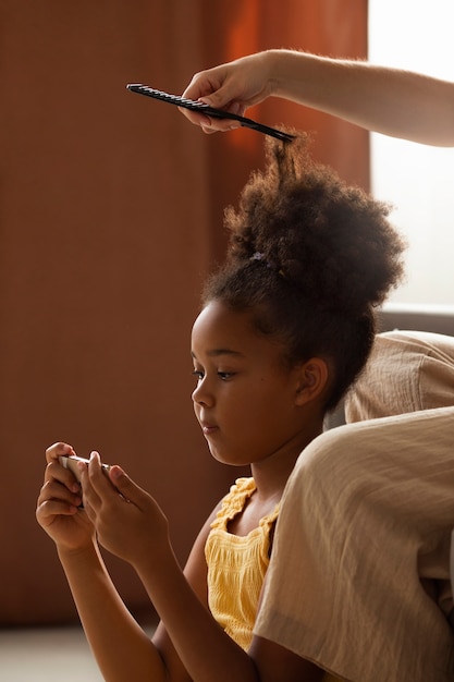 Foto gratuita mamá ayudando a su hijo a peinar el cabello afro