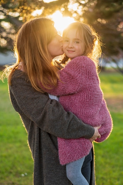 Foto gratuita mamá besando a la hija inocente vista frontal