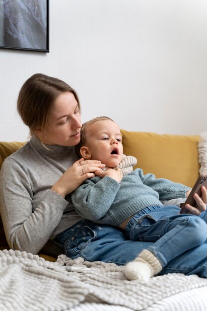 Mamá cuidando a su hijo y teleconsultando con el médico