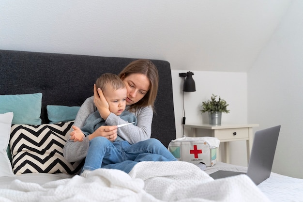 Mamá cuidando a su hijo y teleconsultando con el médico