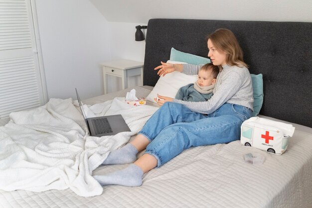 Mamá cuidando a su hijo y teleconsultando con el médico