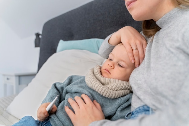 Mamá cuidando a su hijo y teleconsultando con el médico