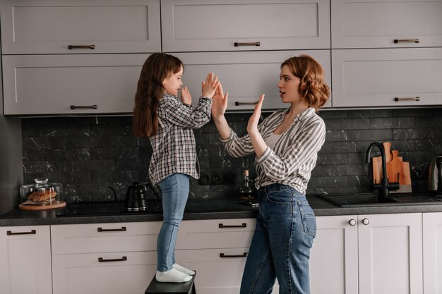 Mamá e hija aplauden y posan en la cocina.