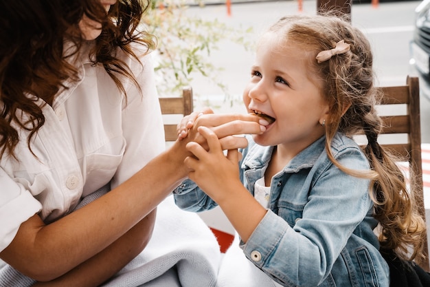 Mamá e hija comen papas fritas en un café al aire libre