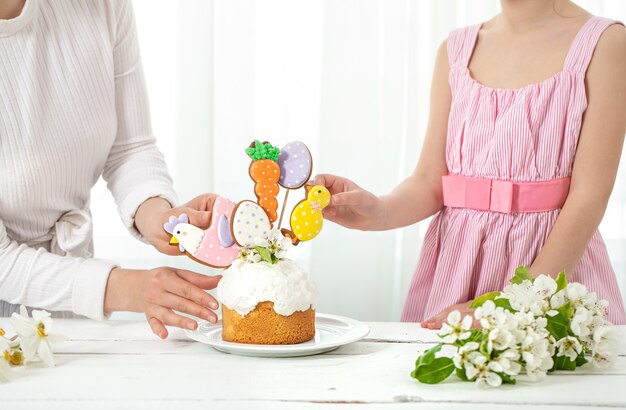 Mamá e hija decoran el pastel pakhsal. El concepto de preparación para las vacaciones familiares de Pascua.