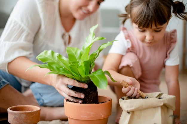 Mamá e hija macetas de plantas de bricolaje en casa