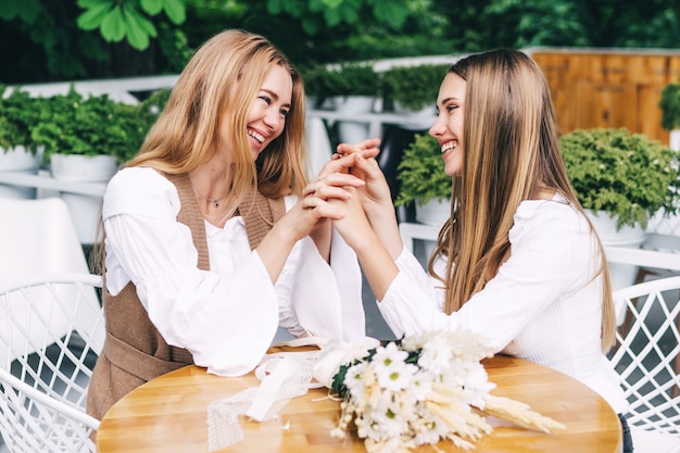 Mamá e hija tomados de la mano y sonriendo en el café