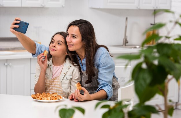 Mamá e hija tomando una selfie en la cocina