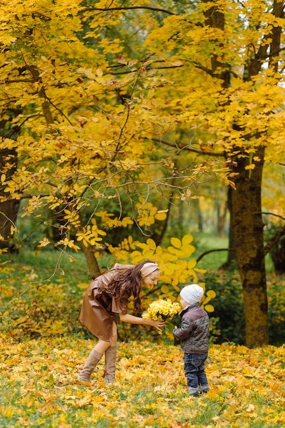 Mamá e hijo caminando y divirtiéndose juntos en el parque de otoño.