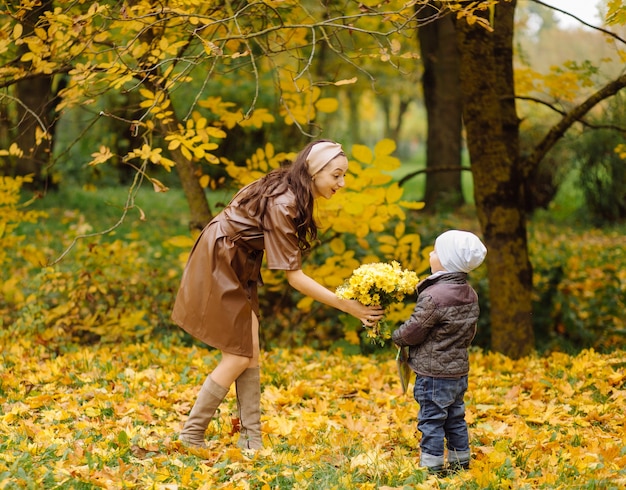 Mamá e hijo caminando y divirtiéndose juntos en el parque de otoño.