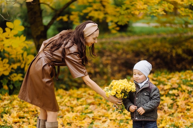 Mamá e hijo caminando y divirtiéndose juntos en el parque de otoño.