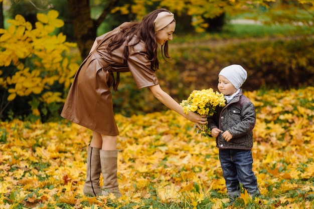 Mamá e hijo caminando y divirtiéndose juntos en el parque de otoño.