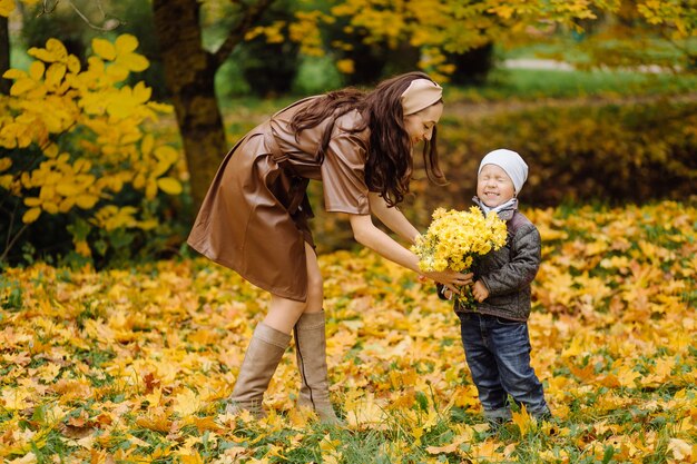 Mamá e hijo caminando y divirtiéndose juntos en el parque de otoño.