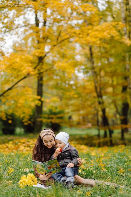 Foto gratuita mamá e hijo caminando y divirtiéndose juntos en el parque de otoño.