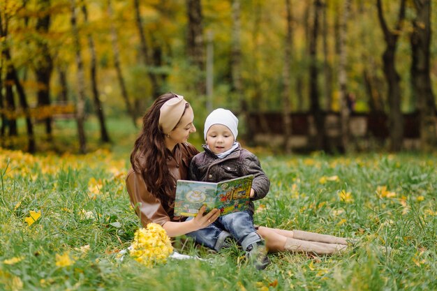 Mamá e hijo caminando y divirtiéndose juntos en el parque de otoño.