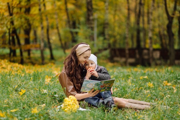 Mamá e hijo caminando y divirtiéndose juntos en el parque de otoño.