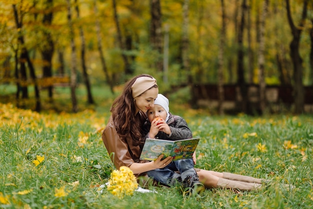 Mamá e hijo caminando y divirtiéndose juntos en el parque de otoño.