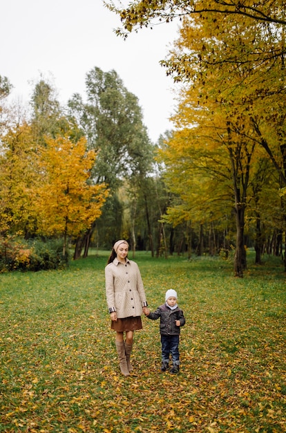 Mamá e hijo caminando y divirtiéndose juntos en el parque de otoño.