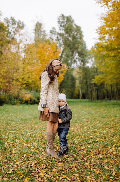 Mamá e hijo caminando y divirtiéndose juntos en el parque de otoño.