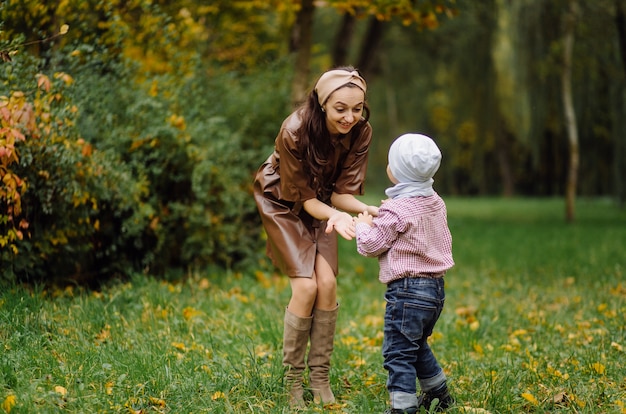 Mamá e hijo caminando y divirtiéndose juntos en el parque de otoño.