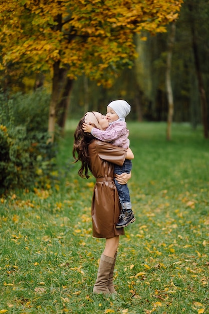 Mamá e hijo caminando y divirtiéndose juntos en el parque de otoño.