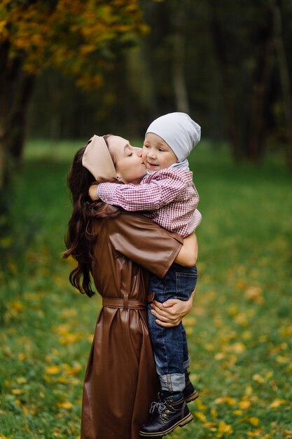 Mamá e hijo caminando y divirtiéndose juntos en el parque de otoño.