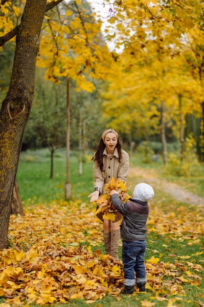 Mamá e hijo caminando y divirtiéndose juntos en el parque de otoño.