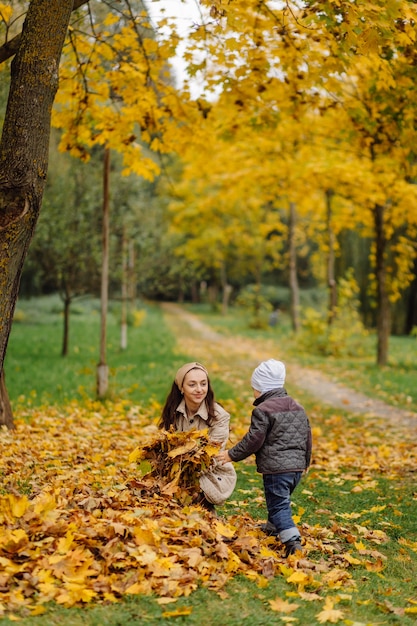 Mamá e hijo caminando y divirtiéndose juntos en el parque de otoño.