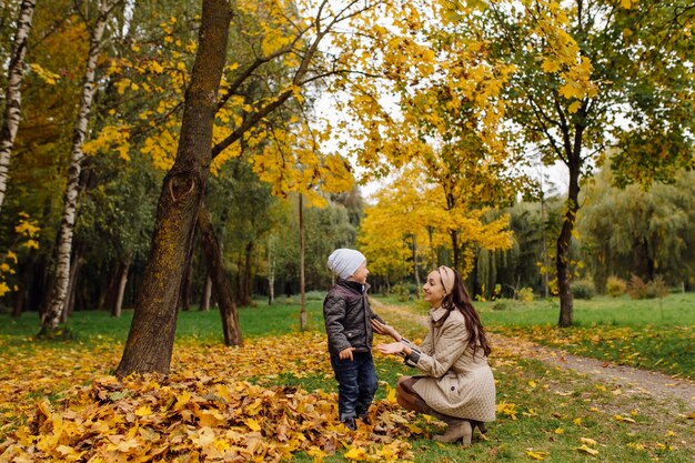 Mamá e hijo caminando y divirtiéndose juntos en el parque de otoño.