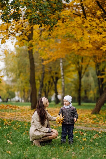 Mamá e hijo caminando y divirtiéndose juntos en el parque de otoño.