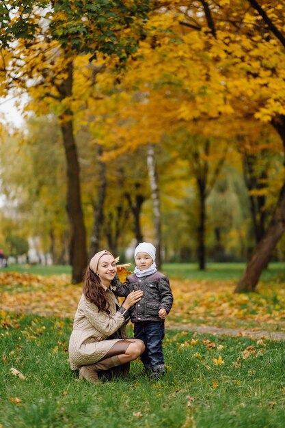 Mamá e hijo caminando y divirtiéndose juntos en el parque de otoño.