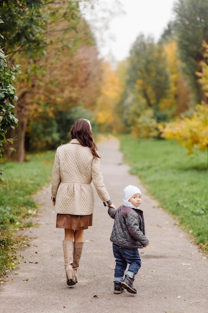 Mamá e hijo caminando y divirtiéndose juntos en el parque de otoño.