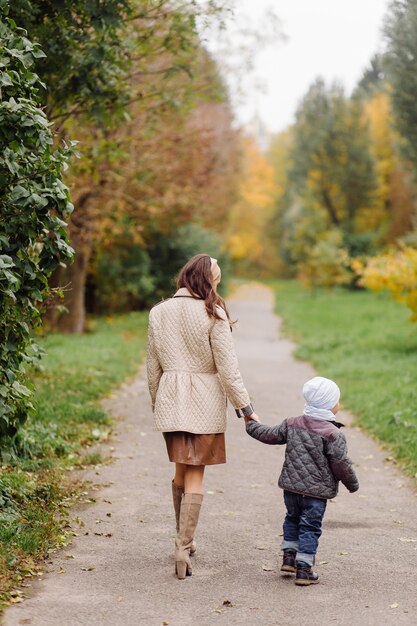 Mamá e hijo caminando y divirtiéndose juntos en el parque de otoño.