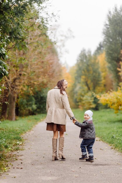 Mamá e hijo caminando y divirtiéndose juntos en el parque de otoño.