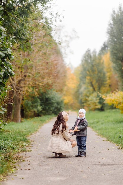 Mamá e hijo caminando y divirtiéndose juntos en el parque de otoño.