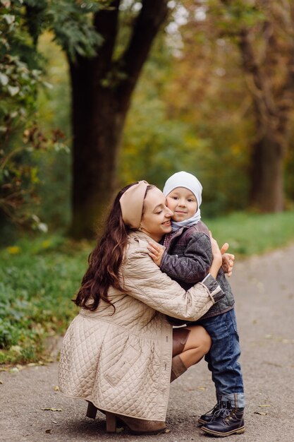 Mamá e hijo caminando y divirtiéndose juntos en el parque de otoño.