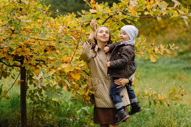 Mamá e hijo caminando y divirtiéndose juntos en el parque de otoño.