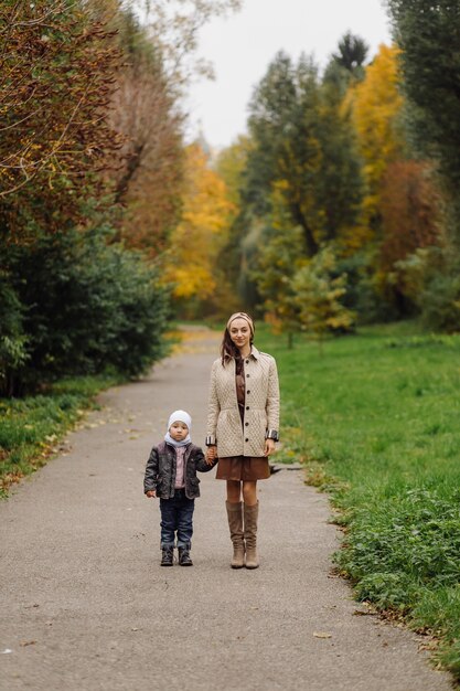 Mamá e hijo caminando y divirtiéndose juntos en el parque de otoño.